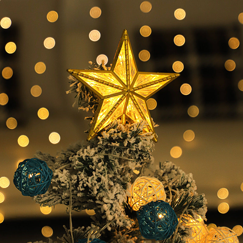 Gold LED star tree topper glowing warm white on top of a frosted Christmas tree with soft fairy lights behind